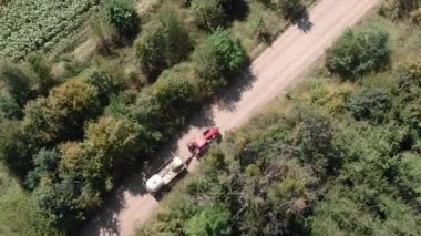 Kırsal yolda püskürtücülü bir traktör. Tarlada çakıllı yolda giden tarım makineleri.