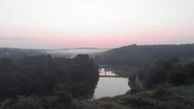 Nehirle birlikte ormanın üzerinde güzel bir gün doğumu. Kırsal alanda pembe gün batımı