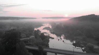 Güneşin sisli nehir üzerinde doğuşunu gösteren hava aracı görüntüsü. Güneşin doğuşuyla birlikte sisli bir nehir. Orman sabah sisli ve sisli. Güneş doğarken güzel destansı kır manzarası