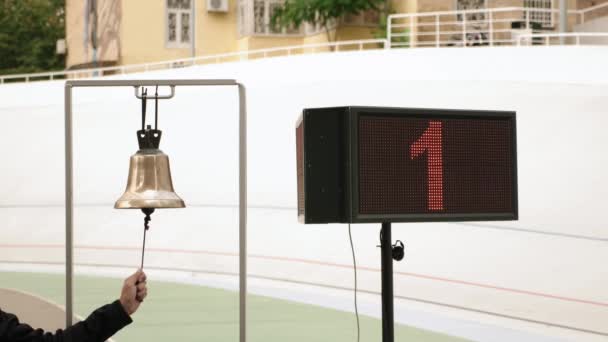 Ciclismo árbitro anel sino no círculo de acabamento na pista de corrida de bicicleta. Placa eletrônica com número de voltas no velódromo — Vídeo de Stock