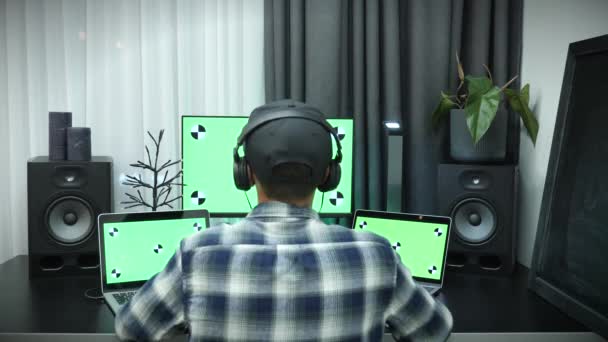 Офис человека в наушниках работает на компьютере с зеленым экраном с широким большим дисплеем — стоковое видео