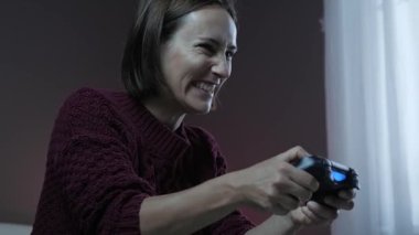 Evde video oyunu oynayan bir kadın. Kız, kablosuz kumanda joystick kullanarak video oyunu oynuyor