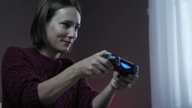 Kadın kumandalı joypad 'de video oyunu oynuyor. Kız oyun oynuyor ve TV ekranına bakıyor