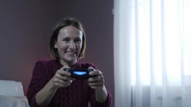 Kız oyuncu, elinde joystick olan konsolda online strateji video oyunu oynuyor