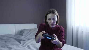 TV karşısında oturan ve joystick ile video oyunu oynayan bir kız. Kablosuz kumanda kullanan heyecanlı kadın