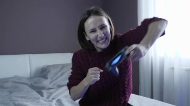 Kablosuz kontrolörle video oyunu oynayan, online oyunu kazanan mutlu kız.