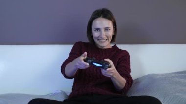 Gülümseyen kadın evde kumandayla video oyunu oynuyor.