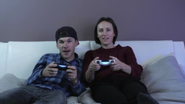 Des amis souriants avec des manettes de jeu jouant à un jeu vidéo à la maison, en utilisant une manette sans fil — Video
