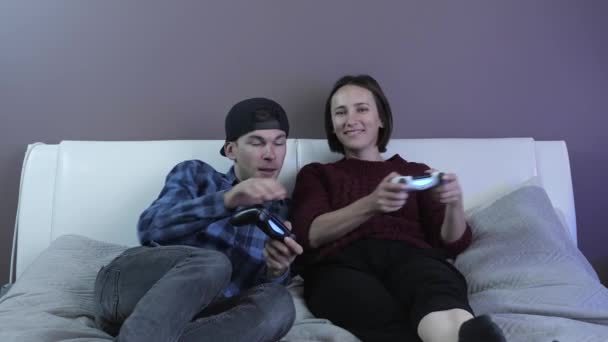Счастливая возбужденная пара, наслаждающаяся видеоигрой, веселясь дома. Концепция семейной деятельности — стоковое видео