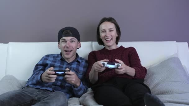 Excited girl and man playing video games on console with wireless controller joysticks — Stock Video