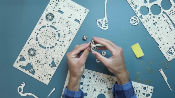 Het assembleren van mechanisch houten puzzelspeelgoed op tafel. Man met kleine stukjes speelgoed in handen — Stockvideo