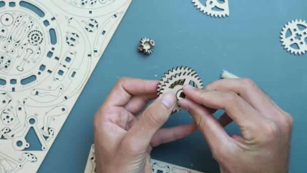 Mechanisch houten puzzelstuk op tafel. Man assemblage van houten kleine stukjes puzzelspeelgoed — Stockvideo