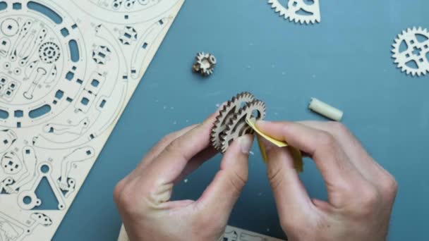 Handen met behulp van schuurpapier om mechanische houten puzzel speelgoed te monteren op tafel thuis — Stockvideo