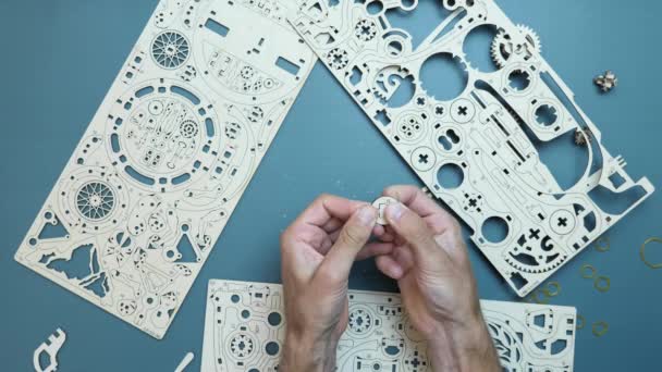 Mann mit Details von Holzpuzzle-Spielzeug. Hände montieren mechanisches Puzzle-Spielzeug — Stockvideo