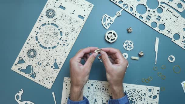 Spel concept. Mechanisch houten puzzelstuk. Man met kleine speelgoedstukjes in handen — Stockvideo