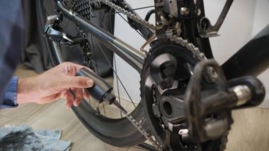 Tamirci bisiklet zincirini yağlar. Bisiklet hazırlığı. Bisiklet tamiratı ve bakımı