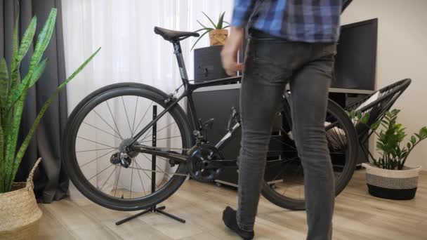 Taller de bicicletas. Mecánico trabajando en taller de ciclismo. Bicicleta colgando en rack de bicicleta — Vídeo de stock