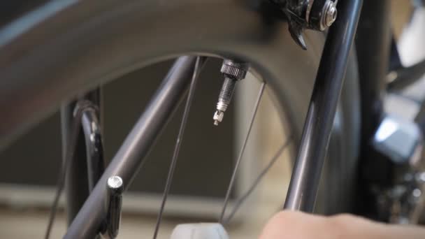 Técnico de bicicleta macho que atornilla la tapa del neumático de la bicicleta después de bombear aire en el neumático usando la bomba de bicicleta — Vídeos de Stock