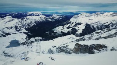 İsviçre Alplerinde kablolu bir araba. Dağlarda karla kaplı teleferik kalkıyor. İsviçre 'deki Rocky karlı dağları. Popüler kış seyahatleri yerleri. Kış açık hava aktivitesi