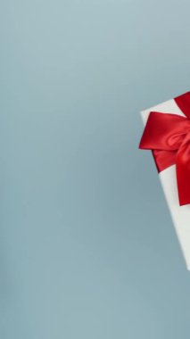 Sevgililer Günü 'nde kadın erkeğe hediye veriyor. Dişi eller, kırmızı kurdeleli hediye paketini erkeğe veriyor. Dikey video