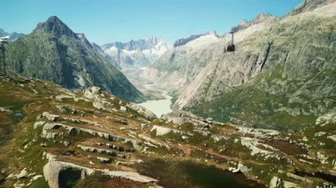 Göl manzarası ve İsviçre Alpleri 'ndeki Grimselpass' ta hareket eden kırmızı teleferik. Kablolu İsviçre dağlarının havadan görünüşü