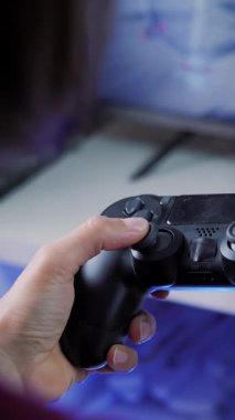 El ele tutuşmalar, oyun kumandasındaki tuşlara basmalar ve televizyon oyunları oynamalar. Kadın evde video oyunu oynuyor, eğleniyor, kablosuz kumanda kumandası kullanıyor. Dikey video