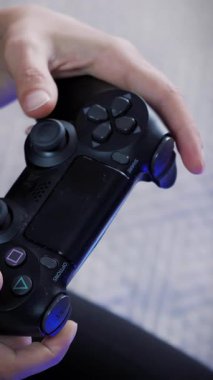 Video oyunu kablosuz kumandalı joystick 'i kapat. Kadın elleri joypad 'de tuşlara basıyor ve basıyor, evde TV karşısında video oyunları oynuyor. Dikey video