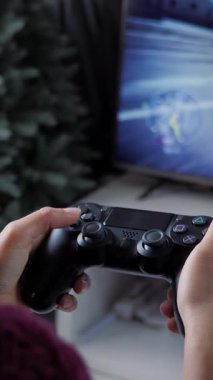 Video oyunu kablosuz kumanda kumandası, kapat. Kızların elleri joypad 'de tuşlara basıyor ve onlara basıyor, evde büyük TV' nin önünde video oyunları oynuyor. Dikey video