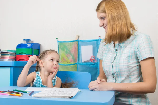 Vijfjarig meisje kijkt grappig naar de tutor die helpt haar om brieven te schrijven juist — Stockfoto