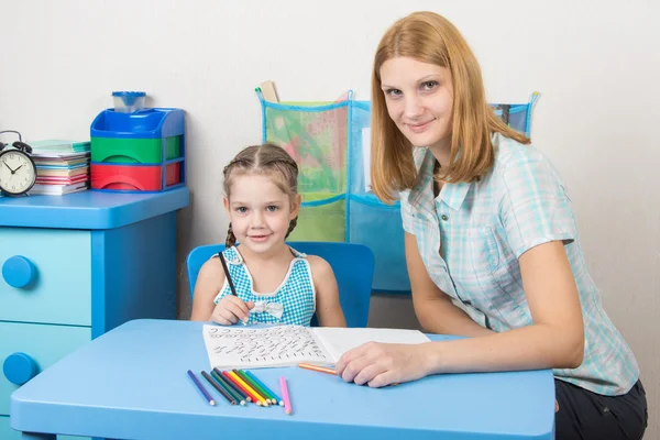 Junges Mädchen sitzt mit einem fünfjährigen Mädchen an einem Tisch und beschäftigt sich mit Rechtschreibung — Stockfoto