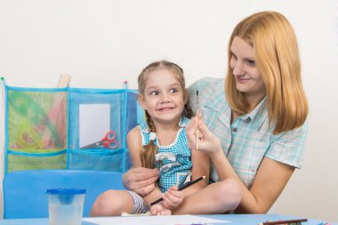 Akıl hocası ve beş yaşındaki kız çizmek için fırça bakarak eğleniyor