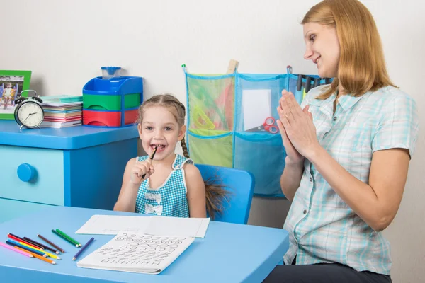 Vijf-jarig meisje en een tutor is leuk zittend aan tafel en geniet van — Stockfoto