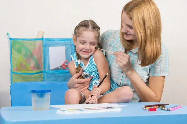 Madre solletica il suo pennello figlia di cinque anni per disegnare — Foto Stock