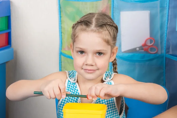 Glückliches fünfjähriges Mädchen spitzt einen Bleistiftspitzer klein — Stockfoto
