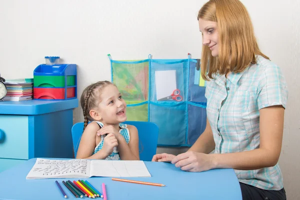 The girl is happy and looks at the teacher in kindergarten — Stock Photo, Image