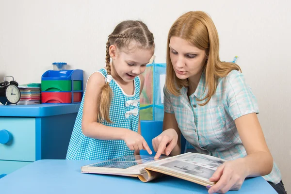 Ragazza e madre di cinque anni che guardano le foto dell'album a tavola a casa — Foto Stock