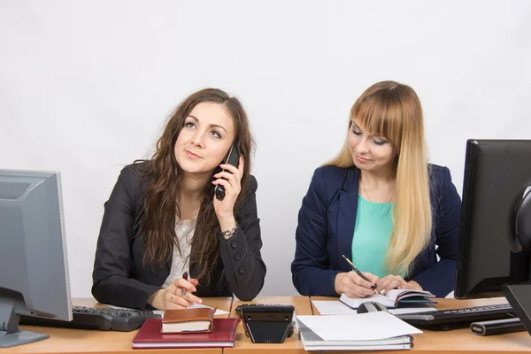 Jonge meisjes in het kantoor, een ander praten aan de telefoon, de ander schrijft in dagboek — Stockfoto