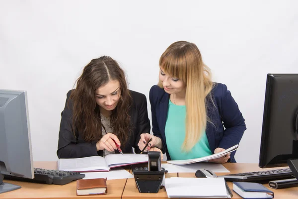 Dos chicas están buscando colegas sentados juntos la información correcta en la misma mesa en la oficina —  Fotos de Stock