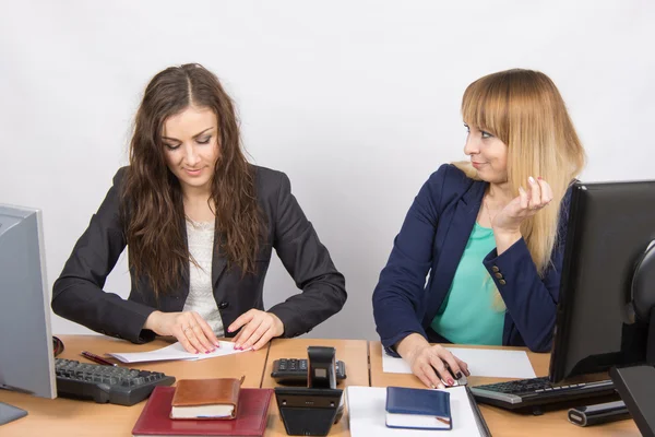 Two young girls working in an office, making a paper airplane, and the second with hatred looks at her — Stock Photo, Image