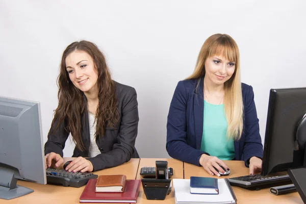 Две молодые девушки, работающие за компьютером, сидят за столом в офисе — стоковое фото