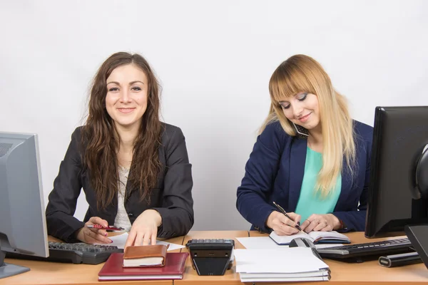 Chicas jóvenes en la oficina, uno mira en el marco, el segundo hablando por teléfono y escribiendo en el diario —  Fotos de Stock