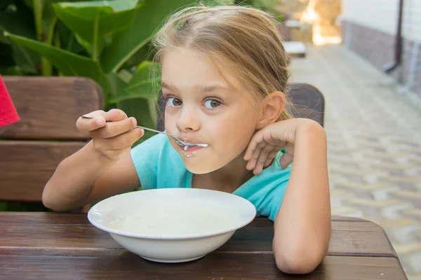 Six-year girl with pleasure eats porridge for breakfast — Stock Photo, Image