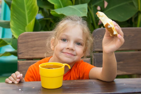Chica sonriendo y comiendo un sándwich con té para el desayuno — Foto de Stock