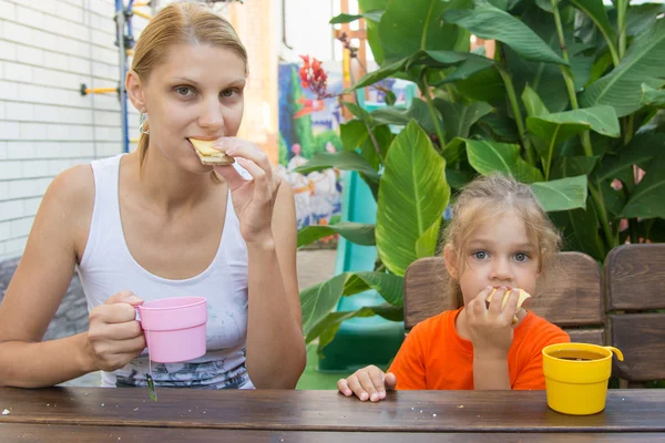 Mamma och dotter med frukost med te och smörgåsar sitter på verandan — Stockfoto