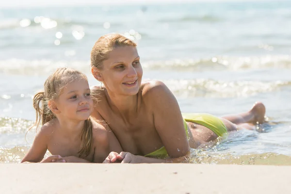 Mom and daughter are in the four-year water on the sandy shore of the sea and looking happily along the coast of the sea — Stock Photo, Image