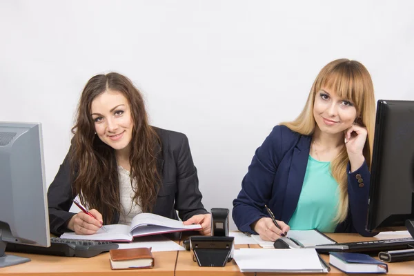 Twee zakelijke vrouwen schrijven in papieren documenten zittend op een bureau en keek in het frame — Stockfoto