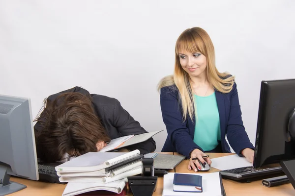 Ofisteki kadın meslektaşları, biri bir yığın klasörün üzerinde uyuyakalmış, ikincisi de ona bakmış. — Stok fotoğraf