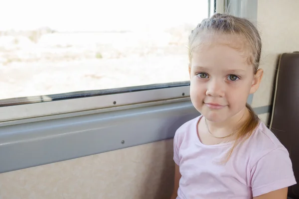 Ragazza felice seduta su una sedia vicino alla finestra in un treno elettrico suburbano — Foto Stock