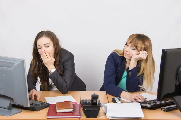 Dos jóvenes empleados de oficina cansados sentados detrás de un escritorio —  Fotos de Stock