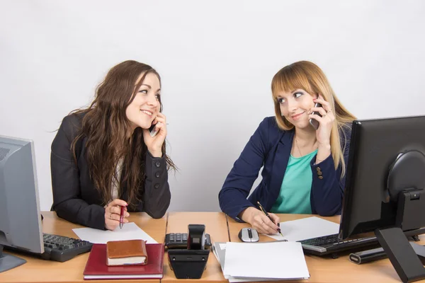 Dos chicas en la oficina hablando por teléfono móvil en su escritorio —  Fotos de Stock